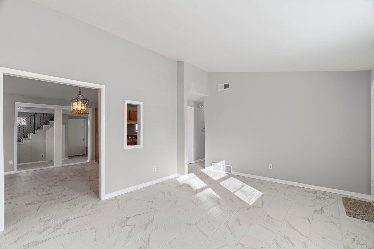 4948 Knight Arnold Road Memphis, TN 38118 - Photo 5 of 27 Spare room with a chandelier, stairway, lofted ceiling, and light marble finish floors