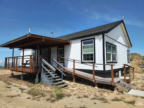 a view of house with wooden deck and furniture