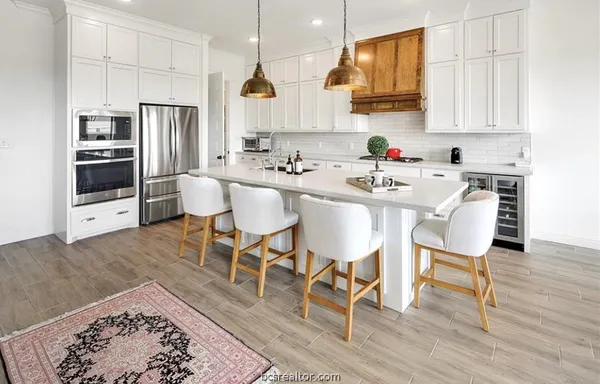 a kitchen with stainless steel appliances granite countertop a table chairs refrigerator and sink