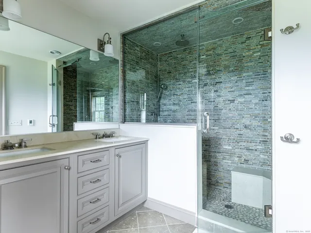 a bathroom with a granite countertop sink a mirror and a shower