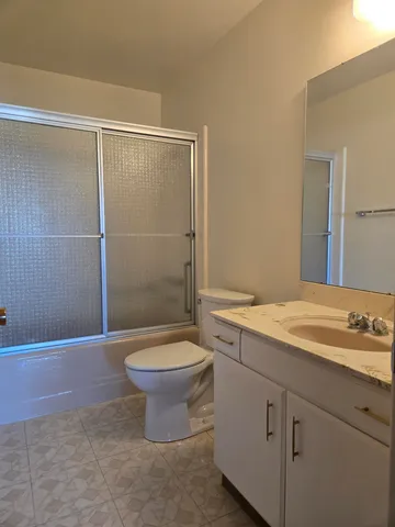 a bathroom with a granite countertop sink a toilet and shower