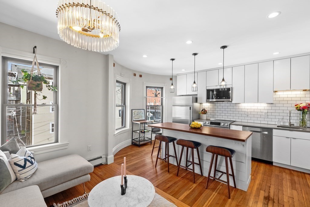 a kitchen with stainless steel appliances granite countertop a stove top oven a sink dishwasher a dining table and chairs with wooden floor