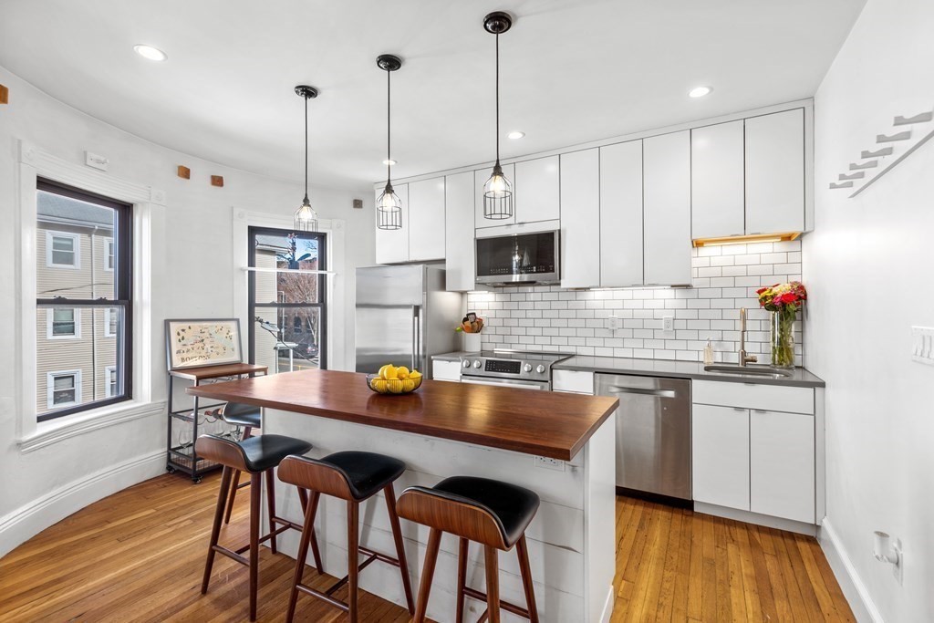 217 Boylston Street, Unit 3 Boston, MA 02130 - Photo 4 of 18 a kitchen with stainless steel appliances granite countertop a stove a sink a kitchen island with a dining table and chairs