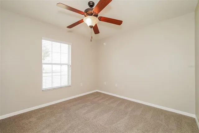 an empty room with a window and a fan