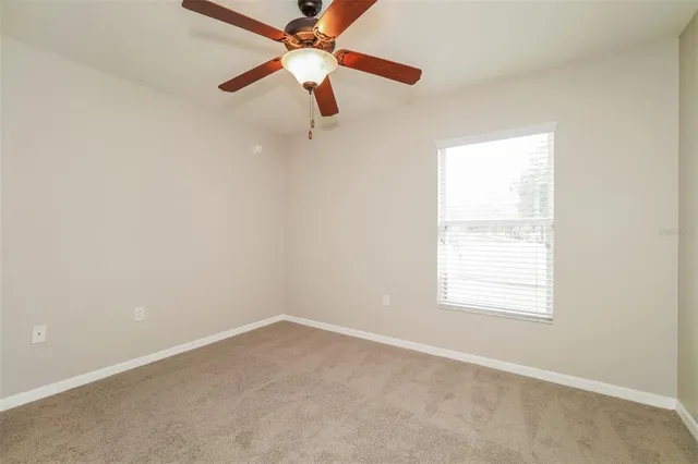 an empty room with a window and a fan