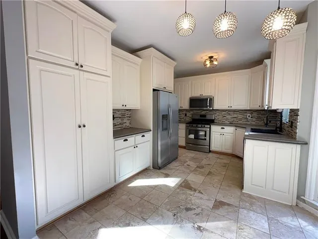 a kitchen with granite countertop a refrigerator stove and microwave