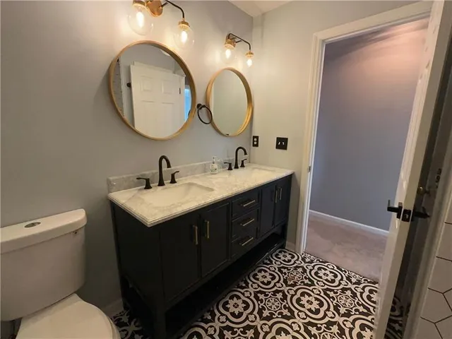 a bathroom with a granite countertop sink a toilet and a mirror