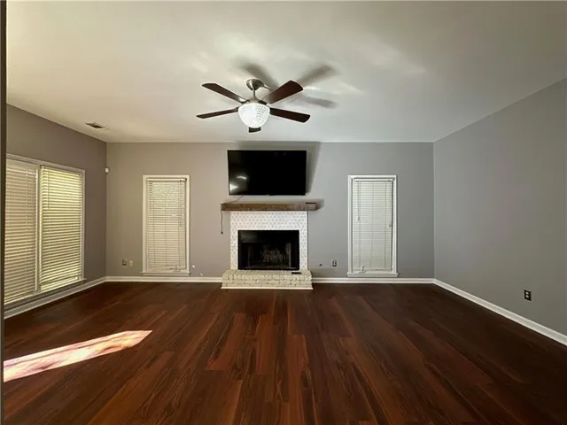 a view of an empty room with wooden floor and a fireplace