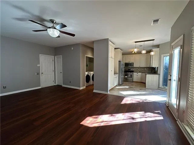 a kitchen with granite countertop a refrigerator a sink and dishwasher a stove top oven with white cabinets