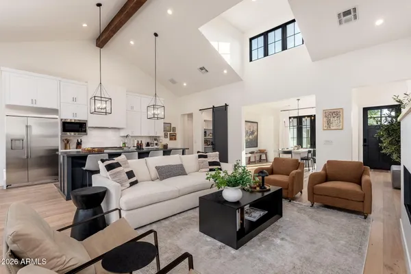 a living room with furniture kitchen view and a chandelier