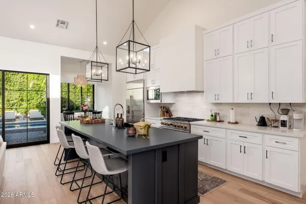 a kitchen with stainless steel appliances a sink a stove a refrigerator and white cabinets with wooden floor
