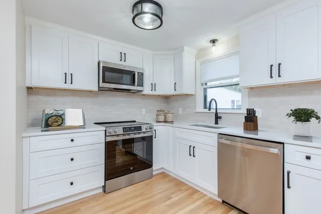 a kitchen with white cabinets stainless steel appliances and sink