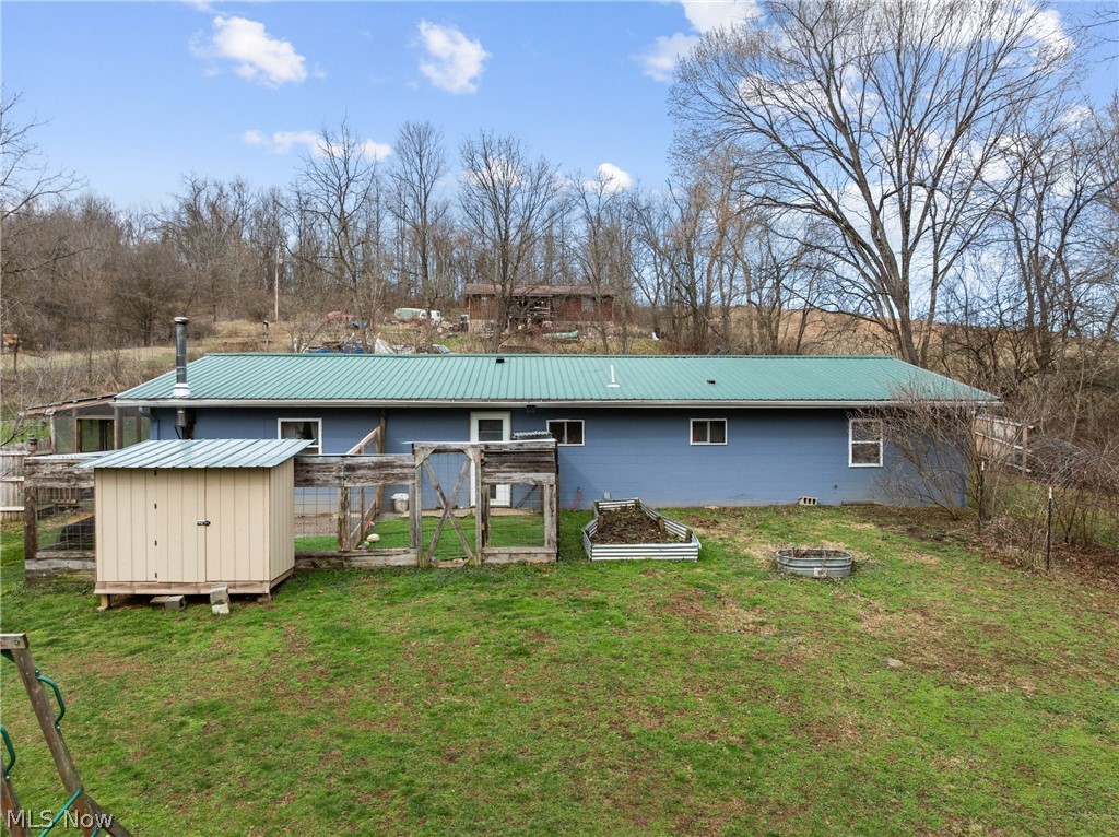 38340 Lees Run Road Cadiz, OH 43907 - Photo 22 of 31 Rear view of property featuring a metal roof, a vegetable garden, and a yard