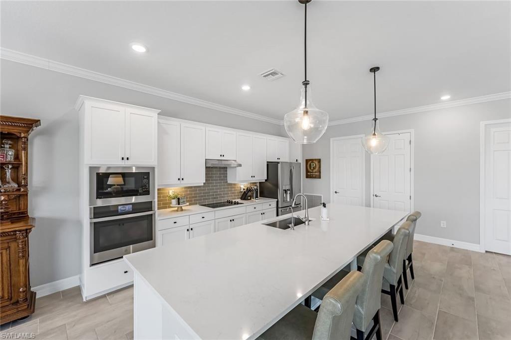 19437 The Pl Boulevard Estero, FL 33928 - Photo 5 of 37 a kitchen with a dining table chairs sink and microwave