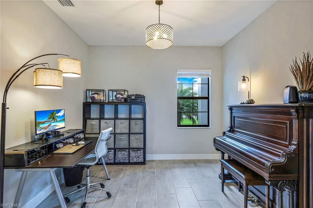 19437 The Pl Boulevard Estero, FL 33928 - Photo 8 of 37 a workspace with a bookshelf a desk and chair with wooden floor