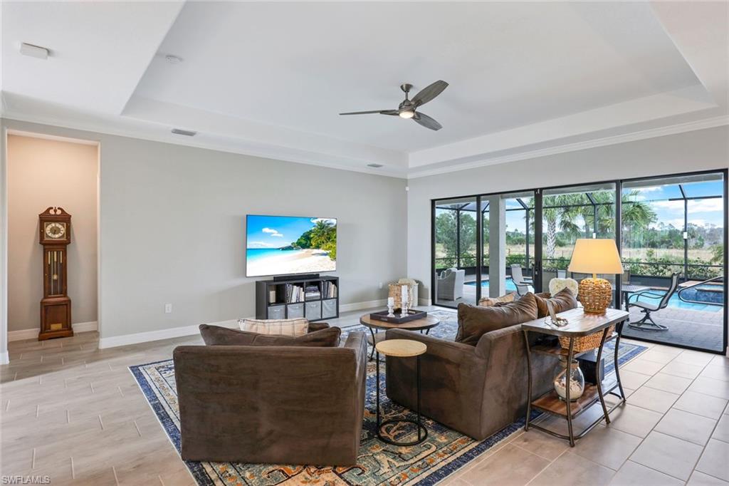 19437 The Pl Boulevard Estero, FL 33928 - Photo 9 of 37 a living room with couches a coffee table and a flat screen tv with wooden floor