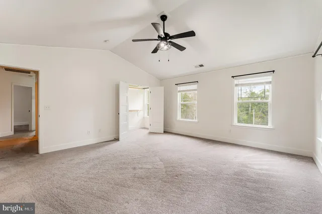 a view of a livingroom with a ceiling fan & windows