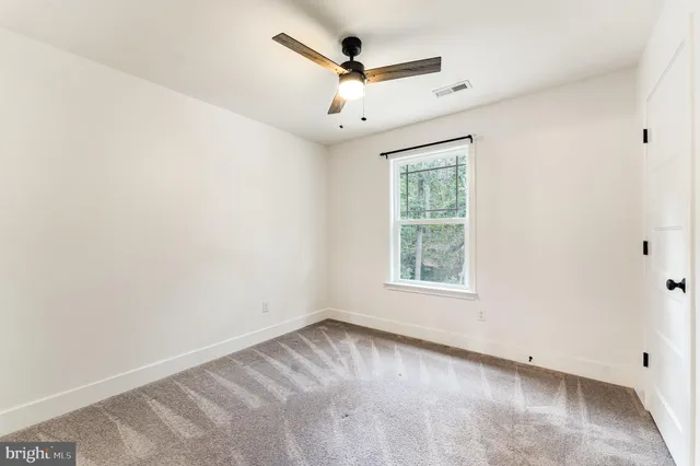 an empty room with a window and a ceiling fan