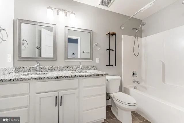 a bathroom with a granite countertop sink toilet a shower and a mirror