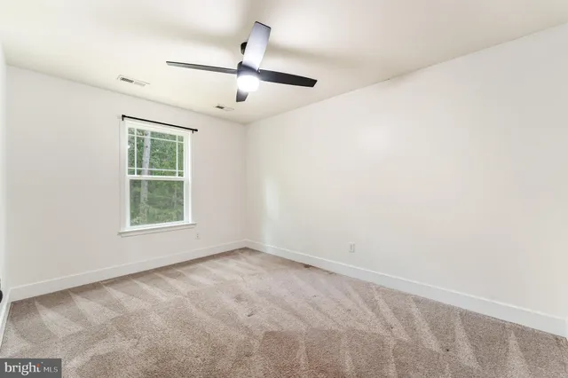 an empty room with a window and ceiling fan
