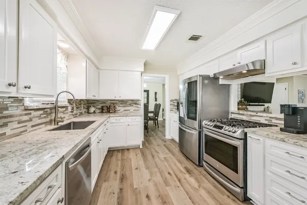 a kitchen with granite countertop a sink stove and refrigerator