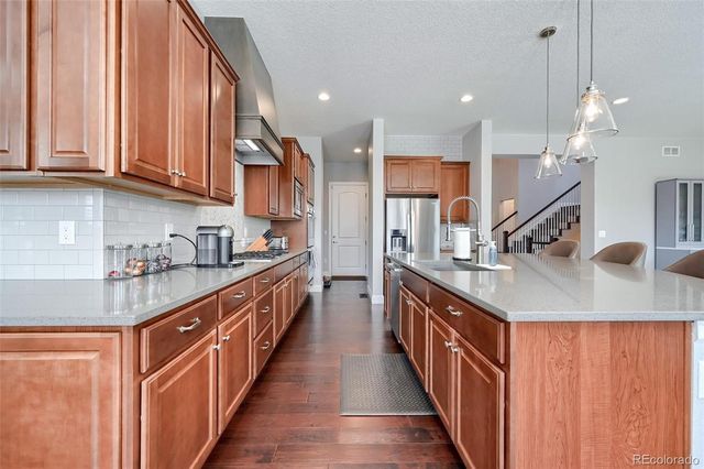 a kitchen with stainless steel appliances granite countertop a sink a stove and a wooden cabinets