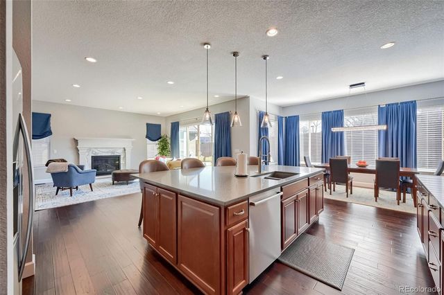 a kitchen with stainless steel appliances granite countertop a stove top oven a dining table and chairs with wooden floor