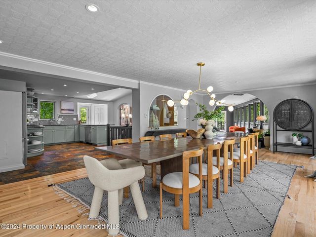 a kitchen with stainless steel appliances granite countertop a stove a sink a oven and a dining table with wooden floor