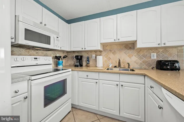 a kitchen with white cabinets and white appliances