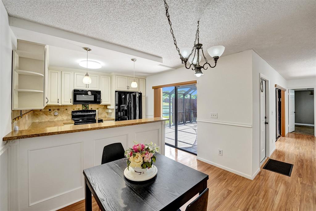 11884 Southwest 12th Place, Unit 11884 Davie, FL 33325 - Photo 17 of 48 a view of a dining room and livingroom with furniture wooden floor a chandelier