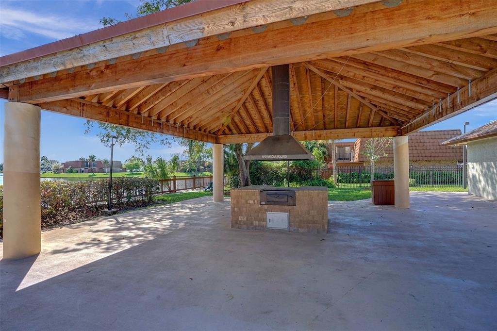 11884 Southwest 12th Place, Unit 11884 Davie, FL 33325 - Photo 46 of 48 a view of a backyard with table and chairs under an umbrella