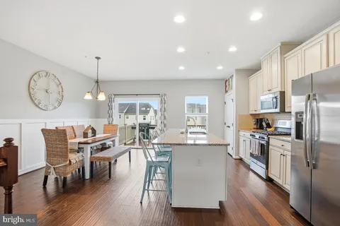 a kitchen with stainless steel appliances a dining table chairs stove refrigerator and cabinets