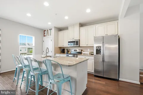 a kitchen with stainless steel appliances granite countertop a refrigerator a stove a sink a dining table and chairs