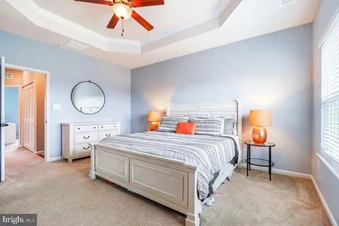 a spacious bedroom with a bed a window and dresser