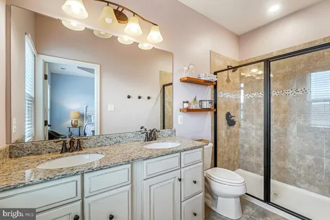 a bathroom with a granite countertop sink a toilet and a large mirror