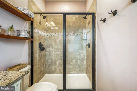 a bathroom with a granite countertop shower a toilet and a sink