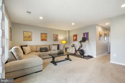 a living room with furniture gym equipment and a ceiling fan