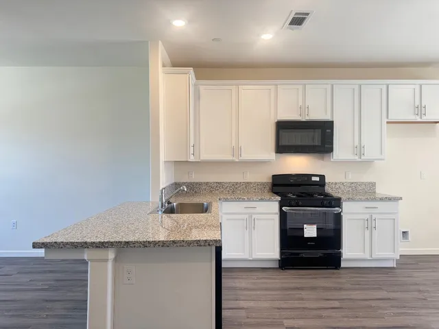a kitchen with granite countertop a sink stove and cabinets
