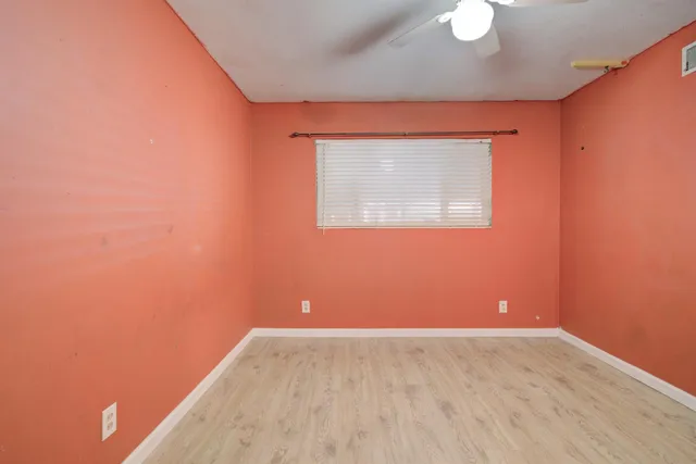 a view of an empty room with closet and wooden floor