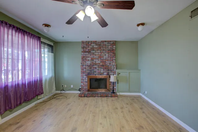 an empty room with windows a fireplace and wooden floor