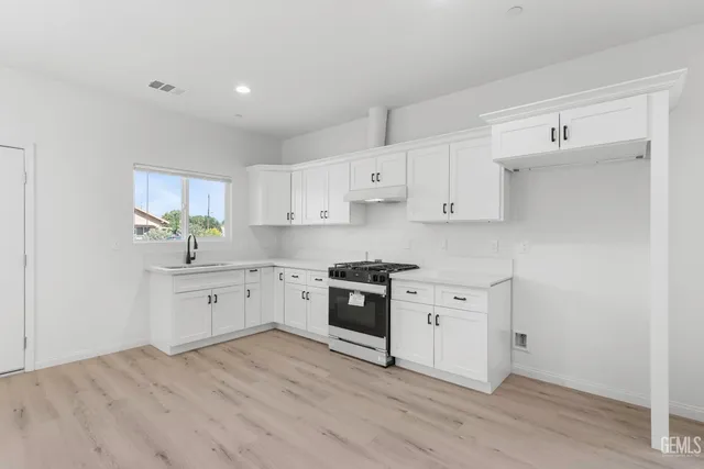 a large kitchen with a white wooden cabinets and a stove top oven
