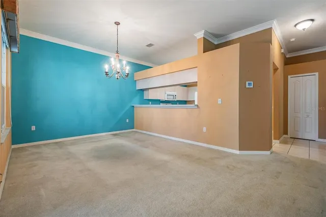 an empty room with windows and chandelier fan