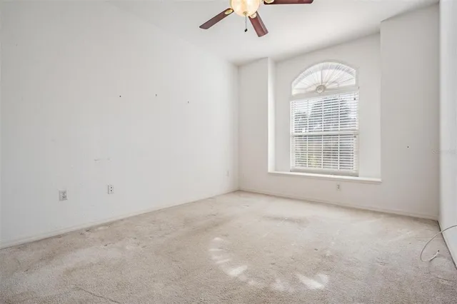 an empty room with a ceiling fan and windows