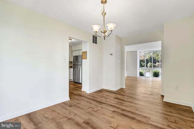 a view of a hallway with wooden floor and a chandelier