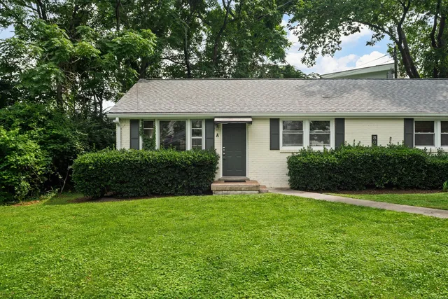 a front view of a house with a yard and trees