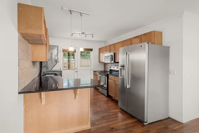 a kitchen with stainless steel appliances granite countertop a refrigerator a sink a stove and a refrigerator