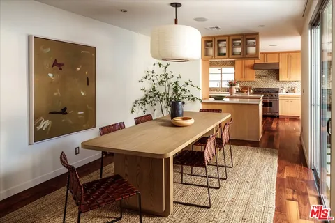 a dining room with stainless steel appliances kitchen island granite countertop a table chairs and a refrigerator