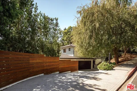 a view of a backyard with table and chairs potted plants and a large tree