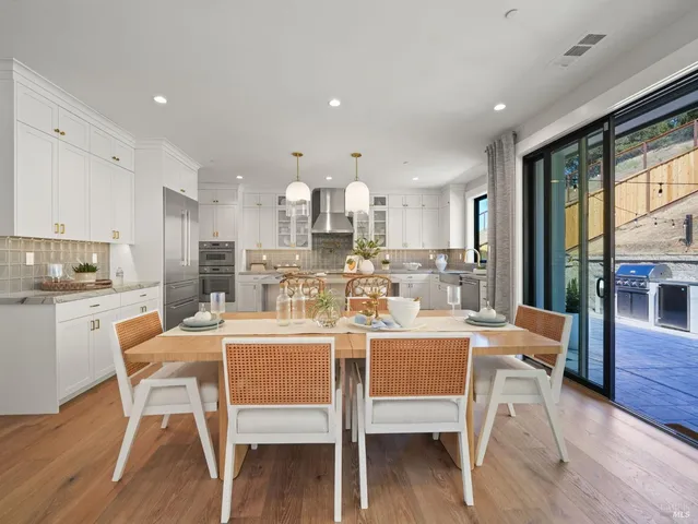 a dining room with stainless steel appliances furniture a large window and a kitchen view