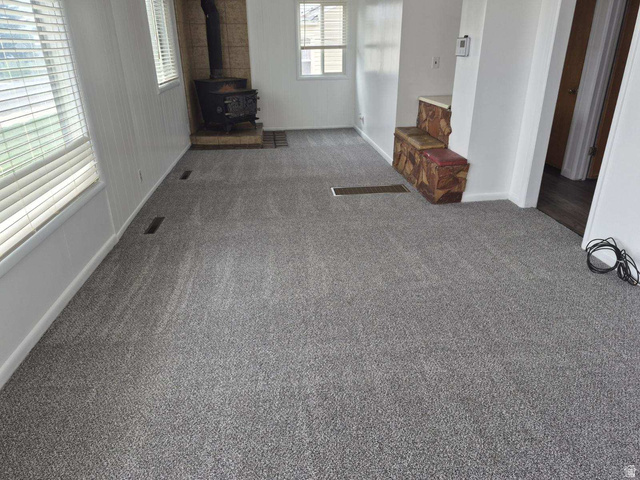 722 Adams Street Montpelier, ID 83254 - Photo 3 of 22 Unfurnished living room with carpet, a wood stove, and plenty of natural light